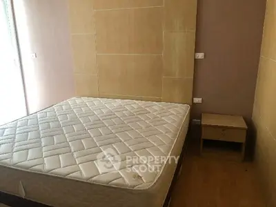 Cozy bedroom with minimalist design featuring a comfortable mattress and wooden nightstand.