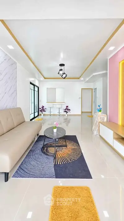 Modern living room with stylish decor, featuring a beige sofa, geometric rug, and elegant lighting.
