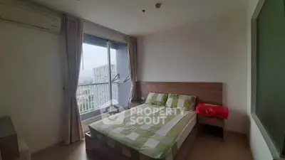 Cozy bedroom with large window offering stunning city views, featuring modern furnishings and natural light.