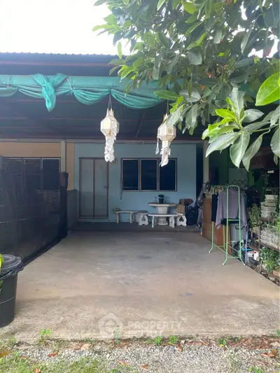 Charming outdoor patio with hanging lanterns and lush greenery, perfect for relaxation and gatherings.