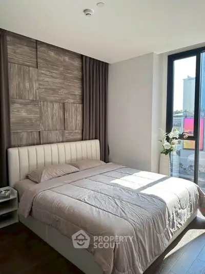 Modern bedroom with stylish decor and large window offering natural light