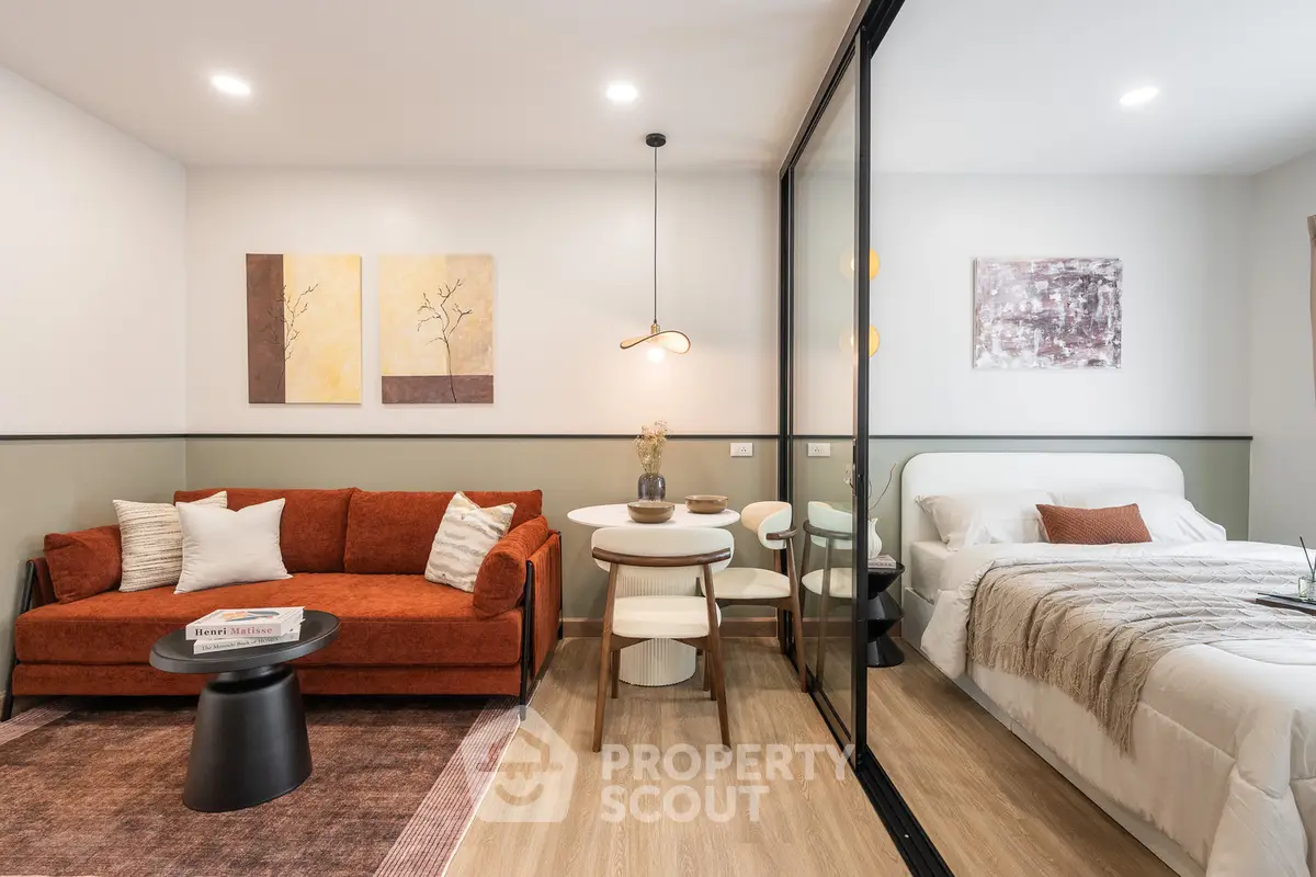 Modern studio apartment with stylish living area and cozy bedroom separated by glass partition.