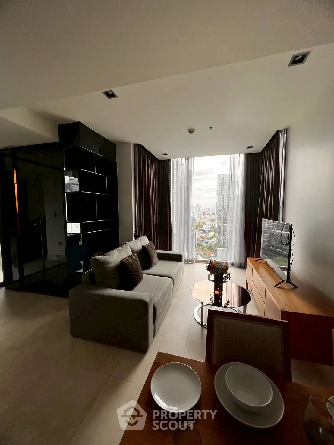 Modern living room with city view, stylish furniture, and natural light.