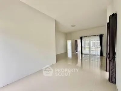 Spacious empty living room with glossy tiled floors and large windows for natural light.