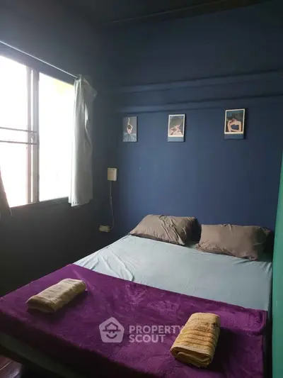Cozy bedroom with blue walls and natural light, perfect for relaxation.