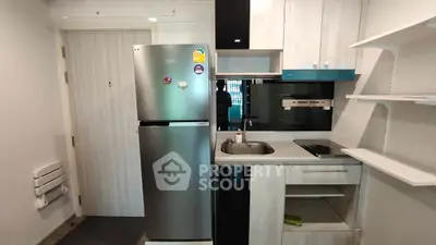 Modern compact kitchen with fridge and built-in appliances in a stylish apartment.