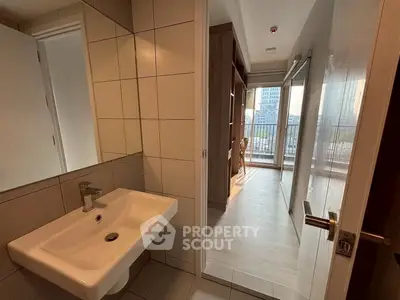 Modern apartment interior with sleek bathroom and bright hallway leading to a balcony with city view.