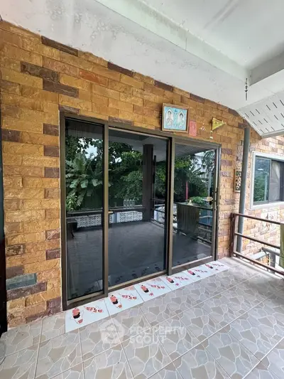 Charming balcony with sliding glass doors and lush green view, perfect for relaxation and outdoor enjoyment.