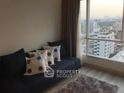 Modern living room with city view, featuring stylish sofa and large windows.