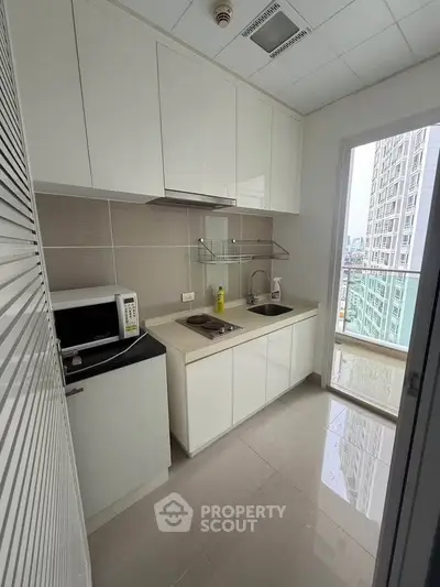 Modern kitchen with sleek cabinets and balcony view in high-rise apartment