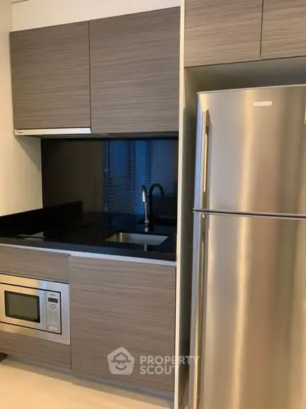 Modern kitchen with sleek cabinetry and stainless steel appliances in a stylish apartment.