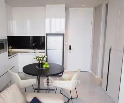 Modern kitchen with sleek white cabinets and cozy dining area in a stylish apartment.