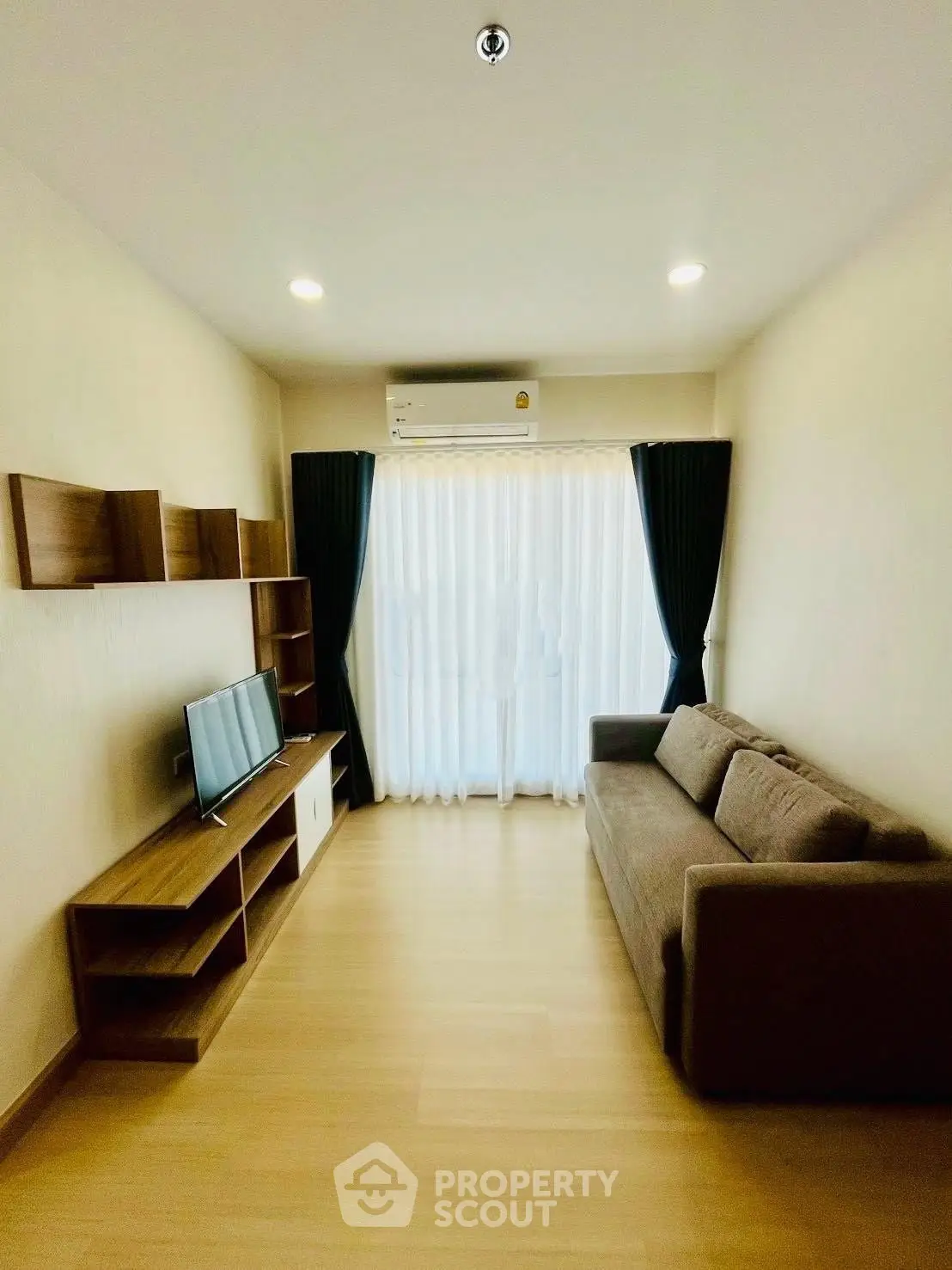 Modern living room with sleek furniture and natural light, featuring a cozy sofa and entertainment unit.