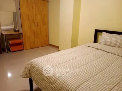 Cozy bedroom with checkered bedding and wooden wardrobe in modern apartment.