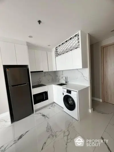 Modern kitchen with sleek appliances and marble flooring in a stylish apartment.