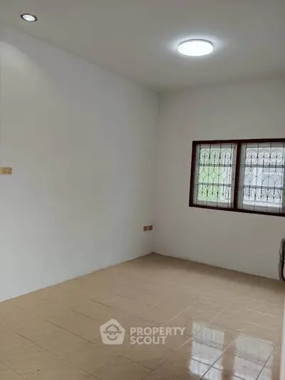 Spacious empty room with tiled floor and natural light, perfect for customization.