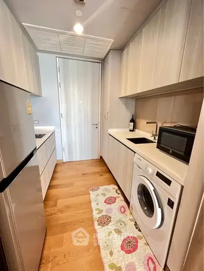 Modern kitchen with washing machine and microwave in sleek design.
