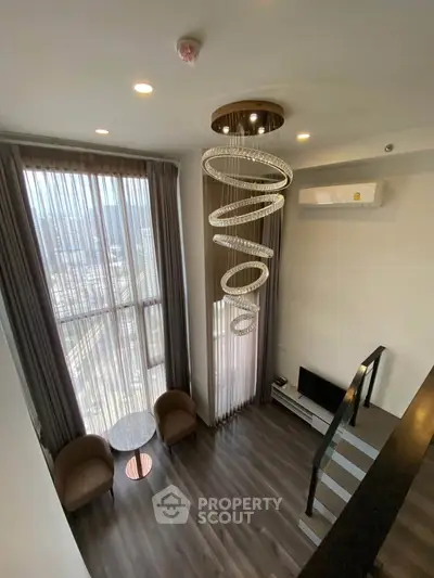 Luxurious high-ceiling living room with modern chandelier and floor-to-ceiling windows offering stunning city views.
