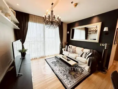 Luxurious living room with elegant chandelier and floor-to-ceiling windows in modern apartment.