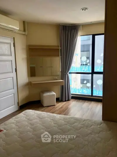 Cozy bedroom with large window and stylish decor in modern apartment.