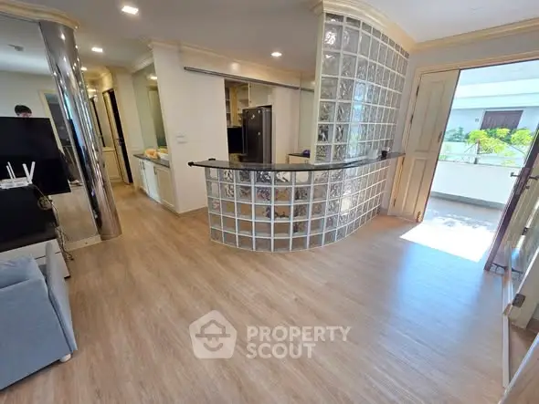 Modern open-plan living area with glass block partition and wooden flooring