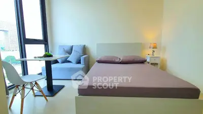 Modern bedroom with city view, featuring cozy bed and stylish seating area.