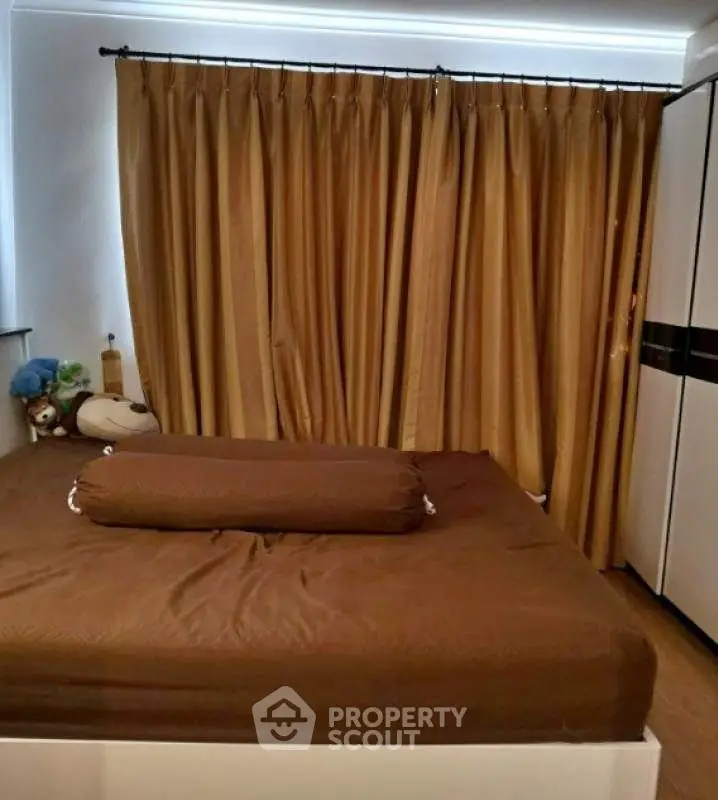 Cozy bedroom with brown curtains and matching bedding, featuring a modern wardrobe.
