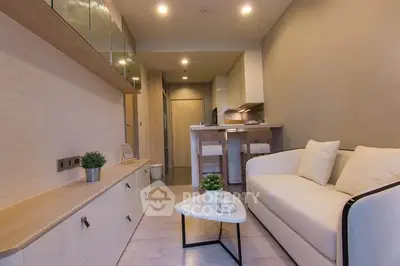 Modern living room with sleek furniture and open kitchen layout in a cozy apartment.