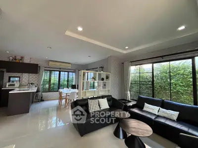 Spacious modern living room with open kitchen and large windows for natural light.