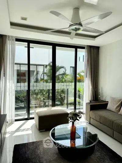 Modern living room with large windows and stylish ceiling fan, offering a bright and airy atmosphere.