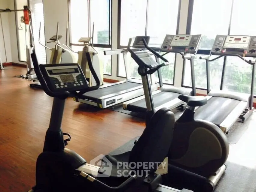 Modern gym with state-of-the-art exercise equipment and large windows offering natural light.