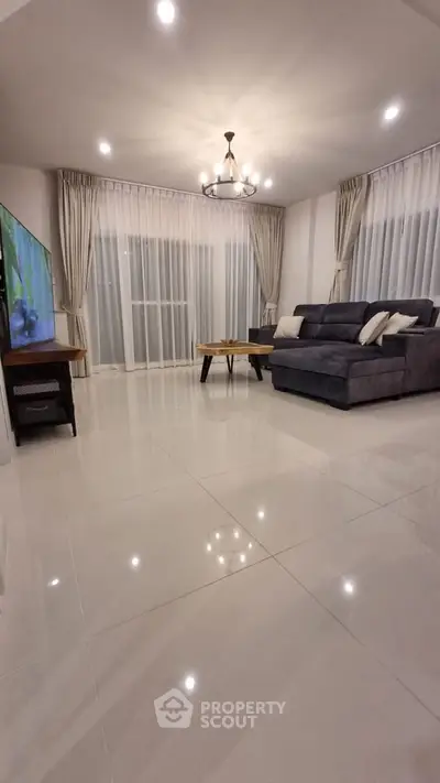 Spacious modern living room with elegant chandelier and large windows.