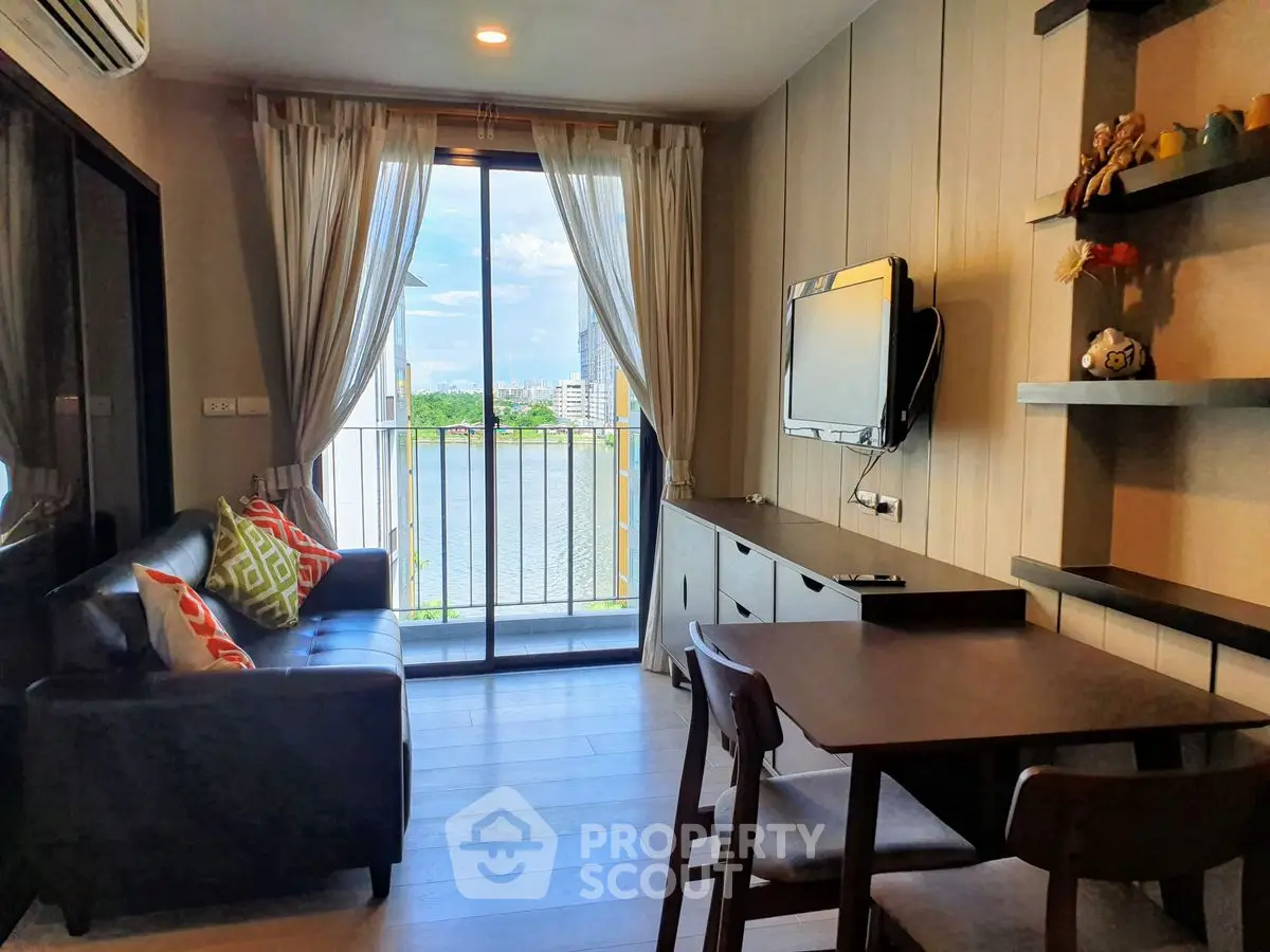 Charming living room with balcony view, cozy seating, and wall-mounted TV in modern apartment.