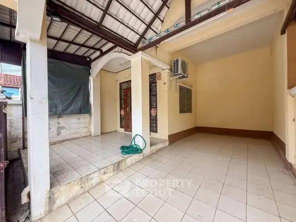 Spacious tiled outdoor area with covered patio and air conditioning unit, perfect for relaxation.