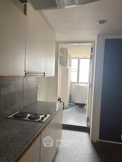 Compact kitchen with electric stove and laundry area in modern apartment