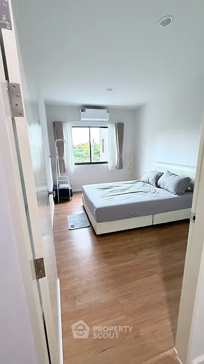 Spacious bedroom with modern decor and large window offering natural light.