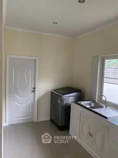 Modern kitchen with sleek washing machine and stainless steel sink, perfect for efficient living.