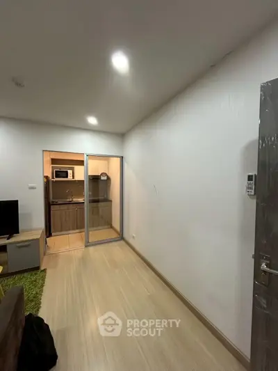 Modern apartment interior with sleek wooden flooring and a compact kitchen area.
