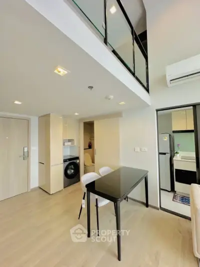 Modern duplex apartment with sleek kitchen and dining area, featuring a washing machine and stylish decor.