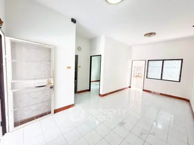 Spacious unfurnished living room with white tiled flooring and ample natural light.