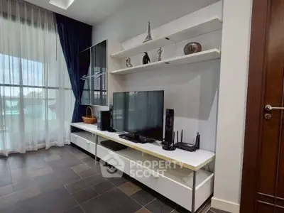 Modern living room with sleek entertainment unit and large window with curtains.