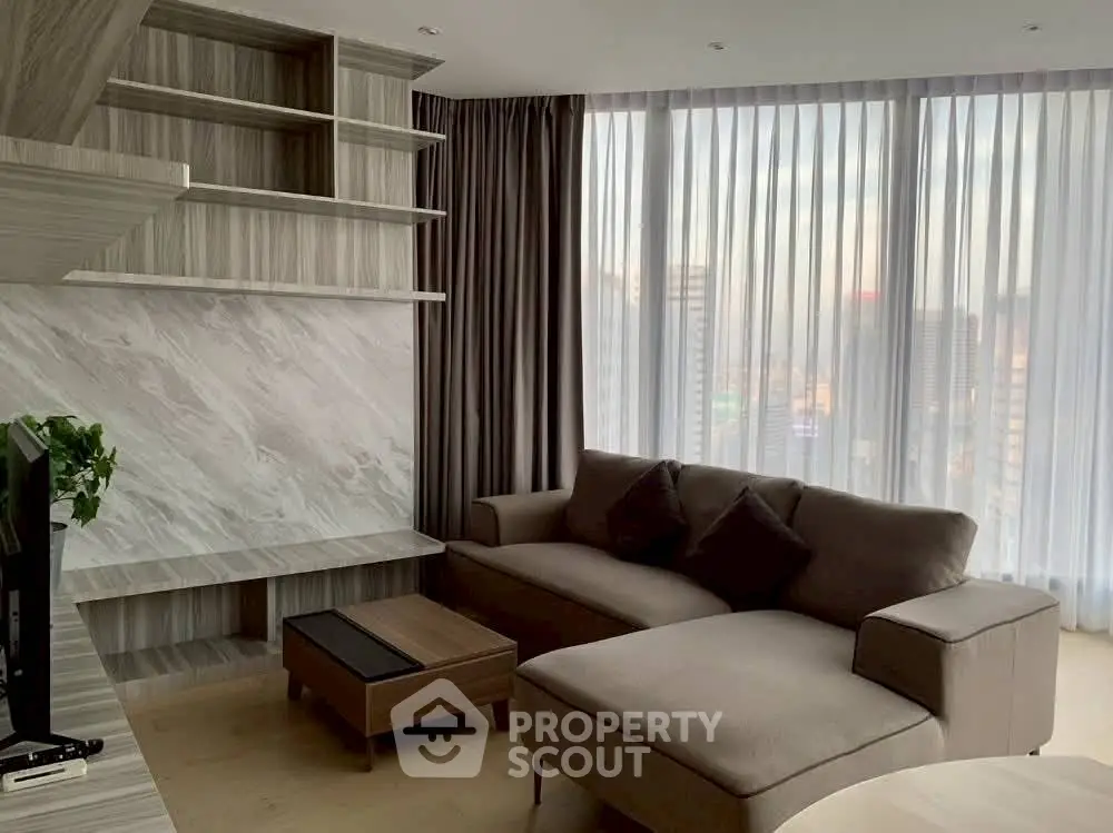 Modern living room with large windows and stylish furniture in a high-rise apartment.