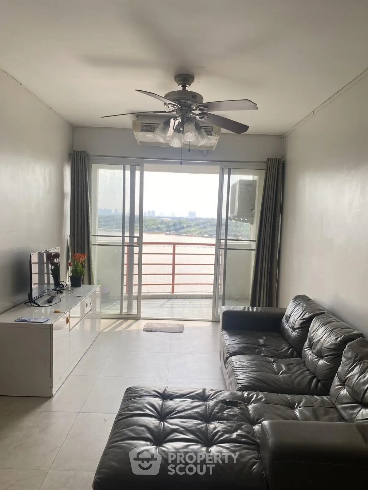 Spacious living room with leather sofa and balcony view in modern apartment