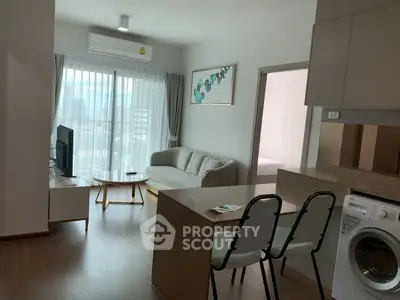 Modern living room with open kitchen and washing machine in a bright apartment.