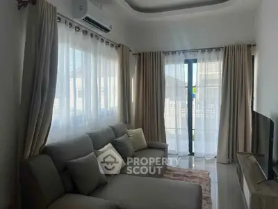 Cozy living room with modern sofa, air conditioning, and natural light from large windows.
