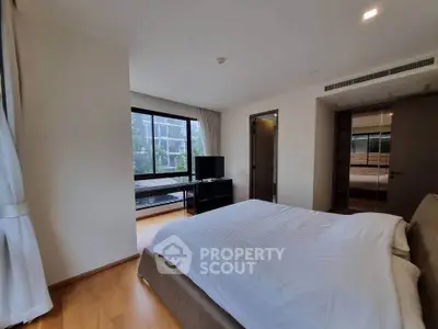 Spacious bedroom with modern decor and large windows offering natural light.