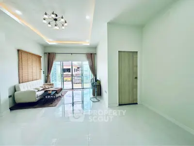 Spacious modern living room with elegant lighting and large windows leading to a balcony.