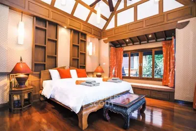 Luxurious bedroom with wooden decor and large windows in a serene setting.