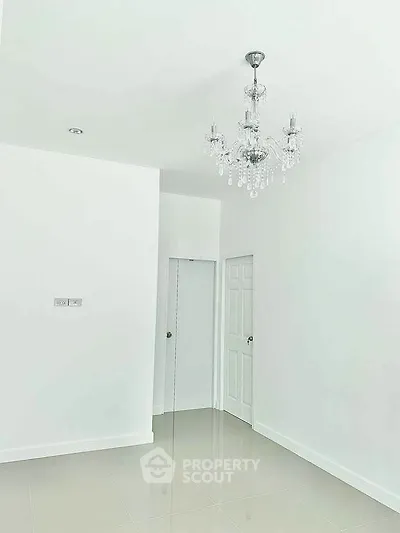 Minimalist white room with elegant chandelier and glossy tiled floor