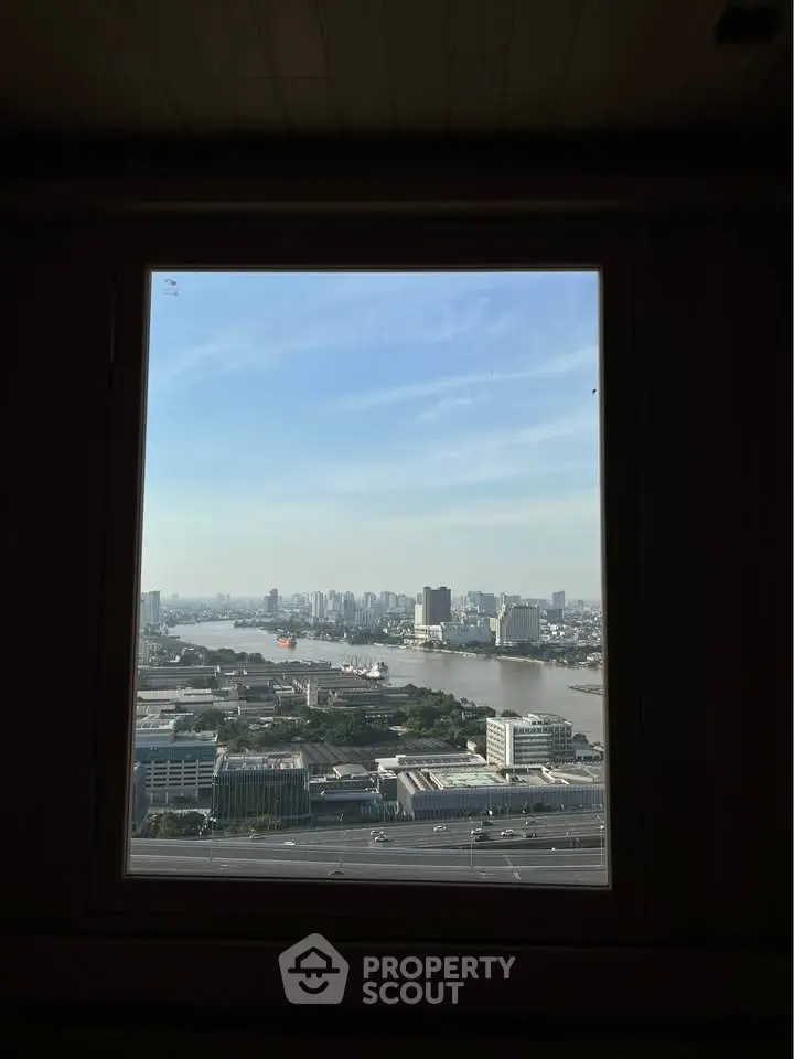 Stunning cityscape view from a high-rise window overlooking a river and skyline.